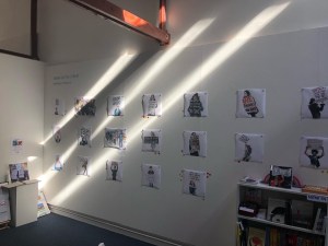 The sun streams into the gallery across a wall of my images