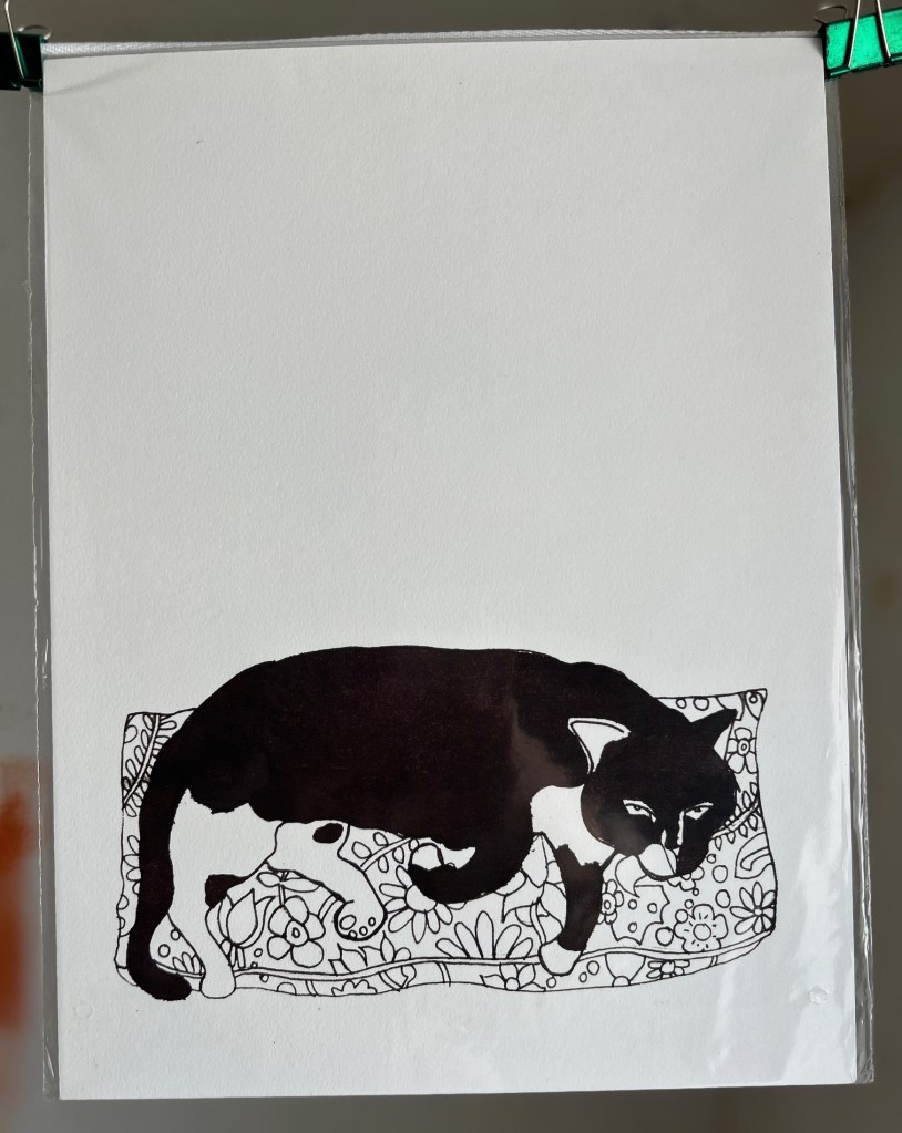 Print of an ink drawing of a sleeping Tuxedo cat, positioned at the foot of a portrait oriented page